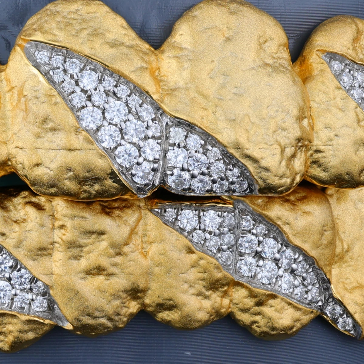 Textured gold-tone grillz with clear stone claw-mark details.