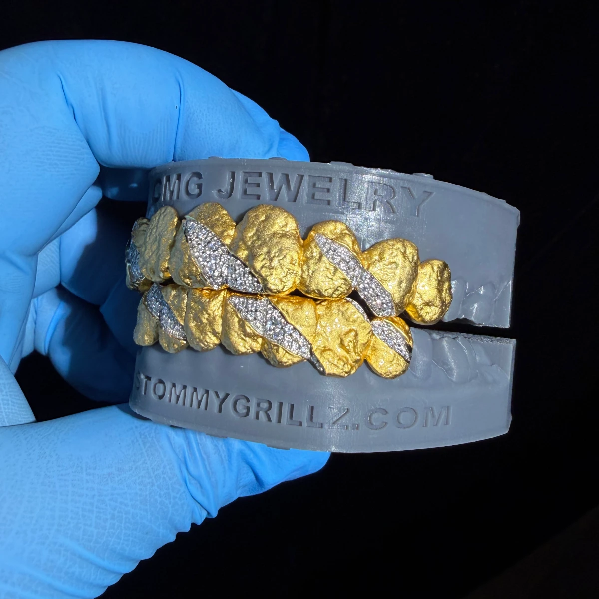 Textured gold-tone grillz with clear stone claw-mark details.