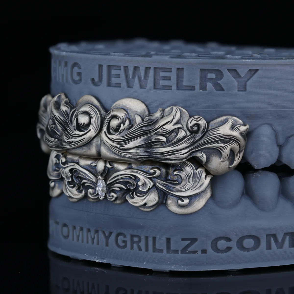 Vintage-style upper and lower grillz with ornate raised scrollwork on a dental model.