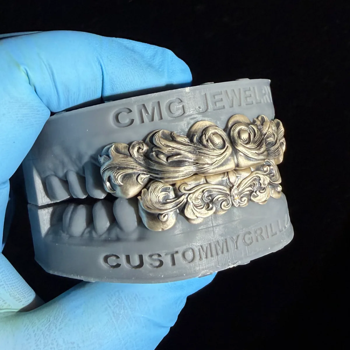 Vintage-style upper and lower grillz with ornate raised scrollwork on a dental model.