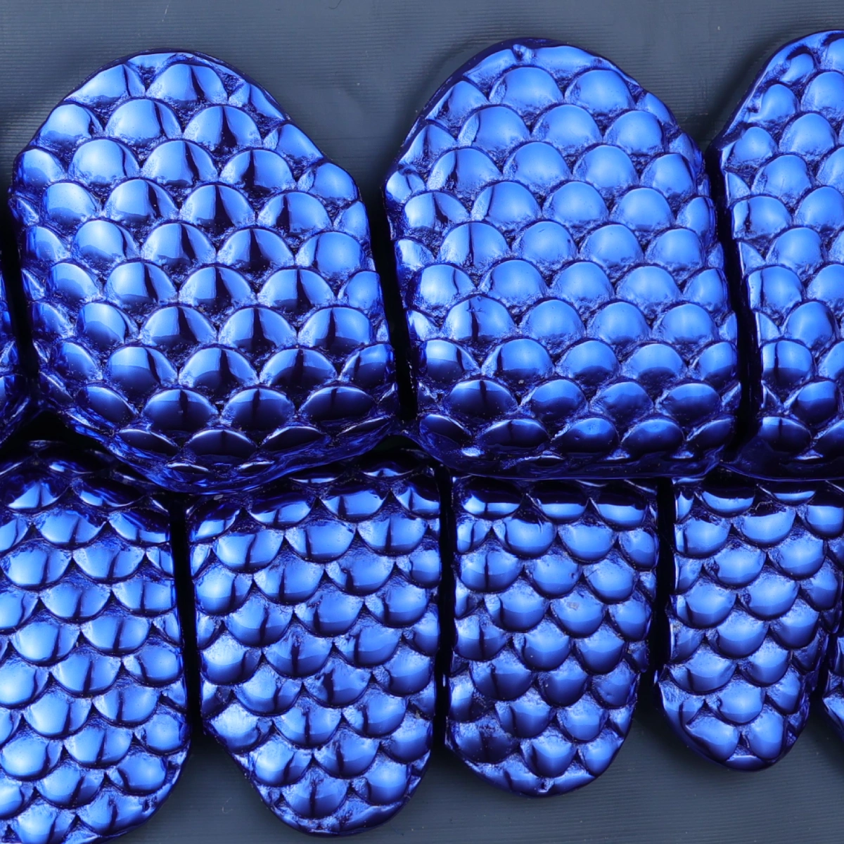 Close-up of the overlapping blue scale texture on custom grillz.